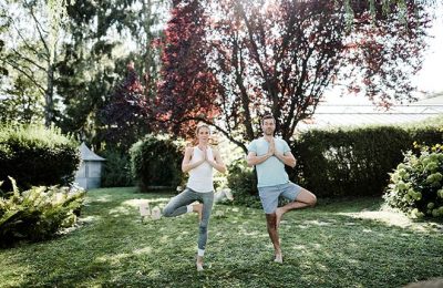Paar macht gemeinsam Yoga im Garten