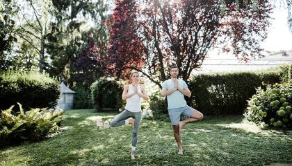 Paar macht gemeinsam Yoga im Garten