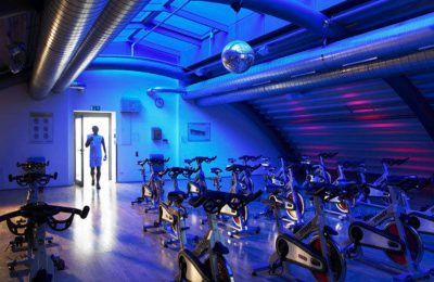 Blau beleuchteter Raum mit Trainingsgeräten im Fitnessclub