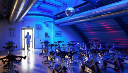 Blau beleuchteter Raum mit Trainingsgeräten im Fitnessclub