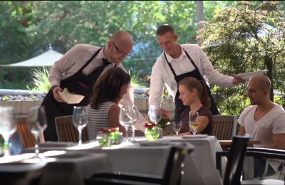 Gruppe wird von zwei Servicekräften im Garten bedient