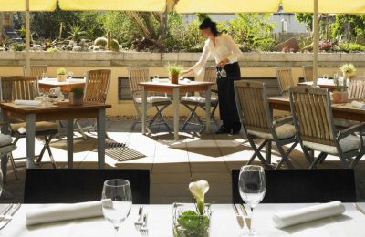 Frau deckt Tisch im Garten