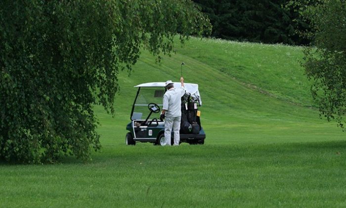 Golfspieler neben Golfcaddy.