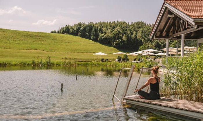 Frau sitzt am Naturbadesee