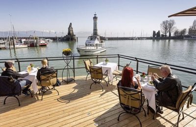 Menschen speisen auf der Hafenterrasse des Hotels