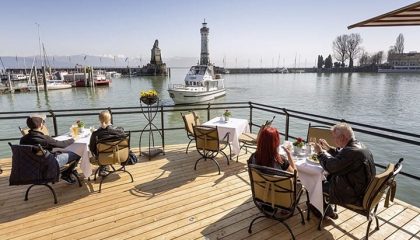 Menschen speisen auf der Hafenterrasse des Hotels