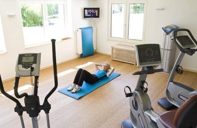 Frau macht Sport im Fitnessraum neben Trainingsgeräten