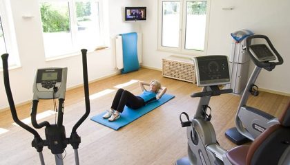 Frau macht Sport im Fitnessraum neben Trainingsgeräten