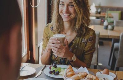 Frau trinkt Latte Macchiato beim Frühstück