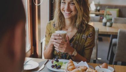 Frau trinkt Latte Macchiato beim Frühstück