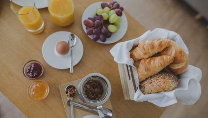 Gedeckter Frühstückstisch mit Kaffee, Orangensaft und Croissants