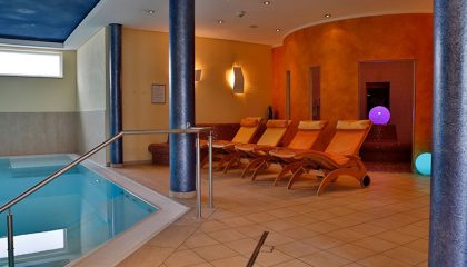 Mehrere Liegen neben dem Indoor Pool