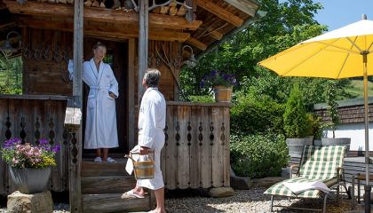 Paar in weißen Bademäntel im Garten vor Hütte