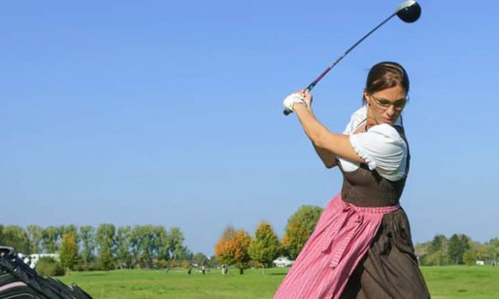 Frau im Dirndl spielt Golf