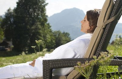 Frau liegt in Liegestuhl im Garten