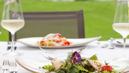 Essen auf der Terrasse neben Weingläsern