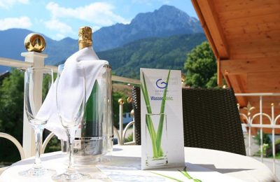 Flasche Sekt auf Tisch am Balkon vor Bergpanorama