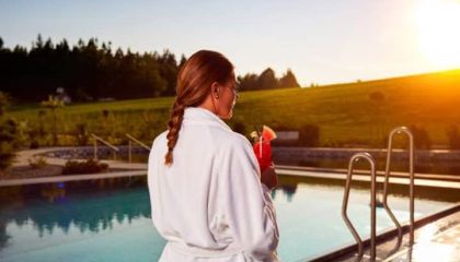 Frau in weißem Bademantel am Außenpool