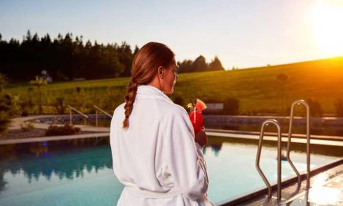 Frau in weißem Bademantel am Außenpool