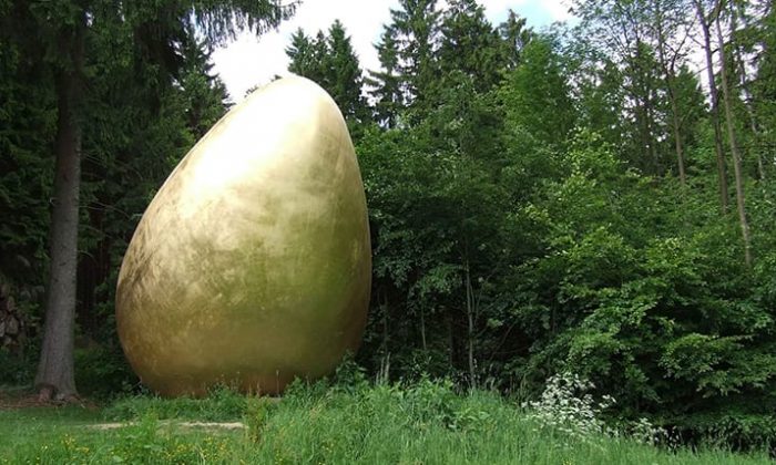 Goldene eierförmige Skulptur im Wald