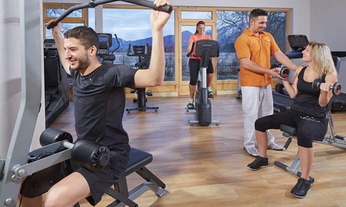 Menschen trainieren an modernen Geräten im Fitnessraum