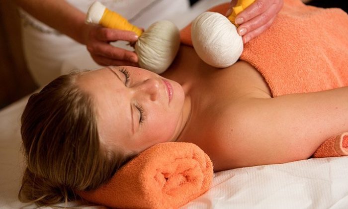 Frau erhält Kräuterstempelmassage