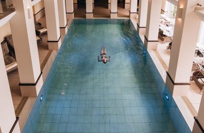 Frau schwimmt Bahn im Indoor Pool im Romantik Hotel Diedrich