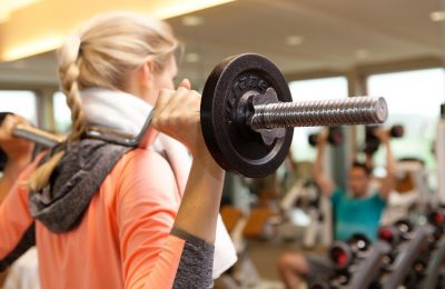 Frau trainiert mit SZ-Stange im Fitnesscenter