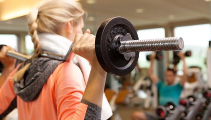 Frau trainiert mit SZ-Stange im Fitnesscenter