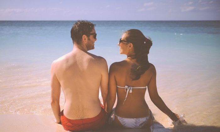 Paar entspannt am Strand mit Füßen im Wasser