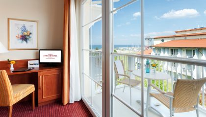 Tisch und Stuhl vor Balkon mit Meerblick im Doppelzimmer