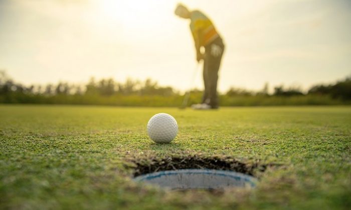 Mann spielt Golf bei Sonnenuntergang