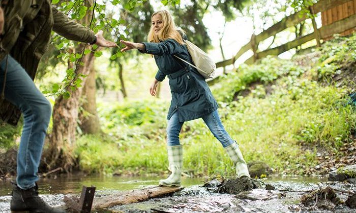 Junges Paar überquert beim Wandern einen Bach