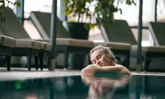 Frau lehnt sich am Beckenrand vom Pool an